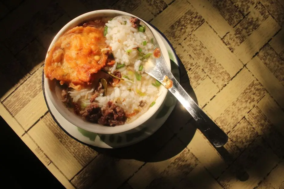 Piring makan anak dengan telur, sayur cincang, dan nasi lembek